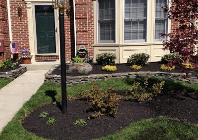 Landscape project infront of a townhouse, planted bushes and carved stone walls